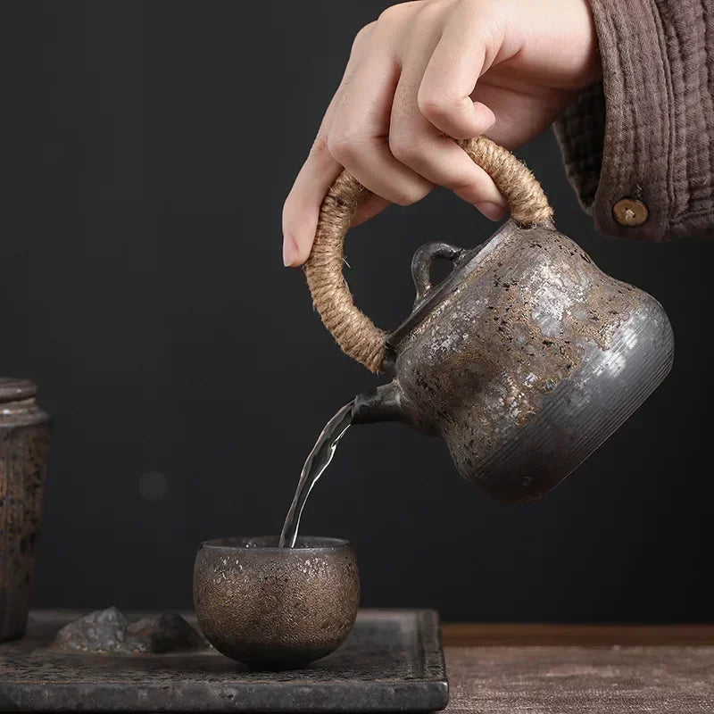 Théière en grès versant le thé dans la petite tasse assortie