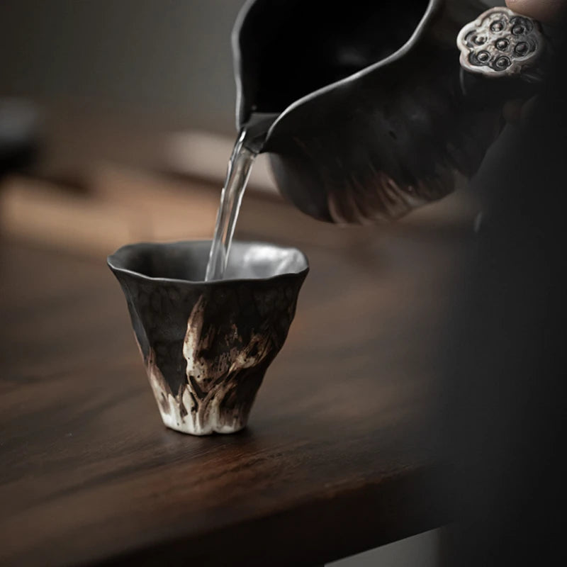 Versement de l'eau chaude dans la tasse à thé en poterie brute