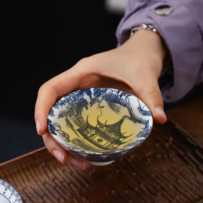 Tasse à thé bleu et blanc remplie de thé, décor de pavillon au fond