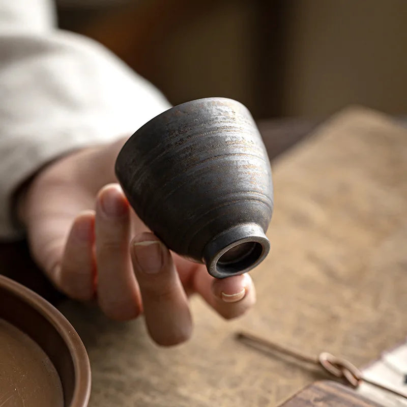 Tasse à thé retournée dans la main, laissant voir son pied