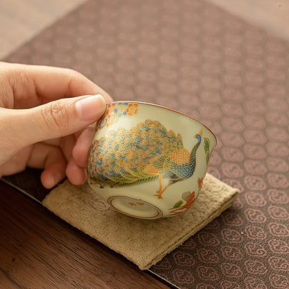 Tasse à thé à motif de paon inclinée sur un coussinet en lin