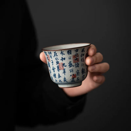 Tasse à thé à décor calligraphié tenue en main sur fond noir