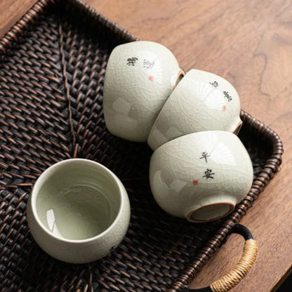 Quatre tasses à thé céladon craquelé disposées sur un plateau tressé