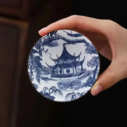 Tasse à thé en porcelaine bleu et blanc tenue entre les doigts