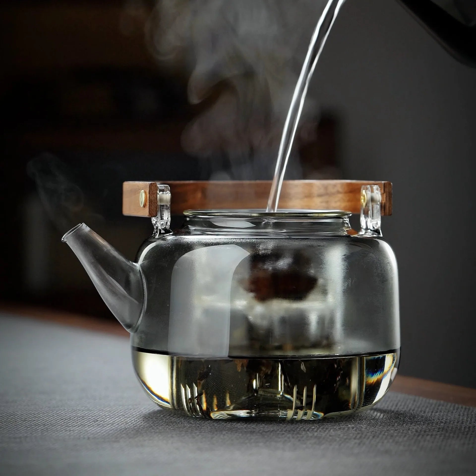 Théière en verre posée sur table avec tasse à thé