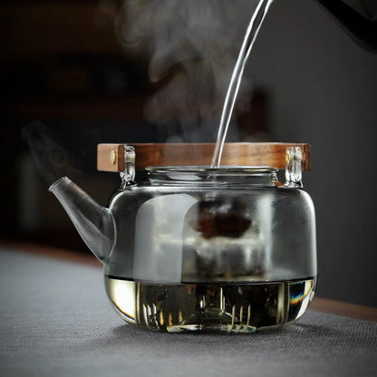 Théière en verre posée sur table avec tasse à thé