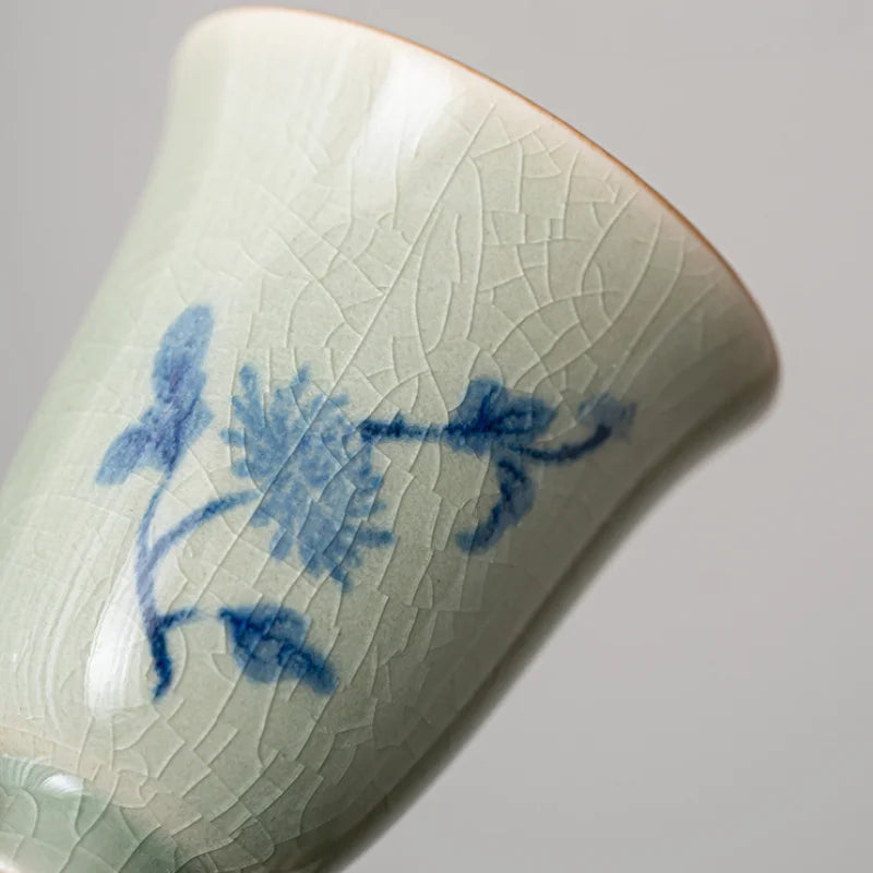 Gros plan du décor floral bleu sur la glaçure craquelée de la tasse