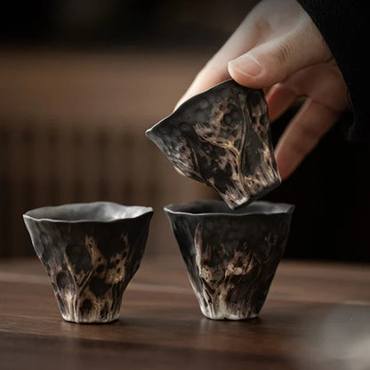 Trois tasses à thé en poterie brute, l'une soulevée au-dessus des autres