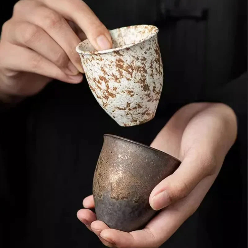 Deux tasses à thé aux glaçures mouchetées tenues à deux mains
