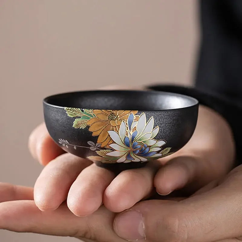 Tasse à thé en céramique noire tenue au creux de la paume