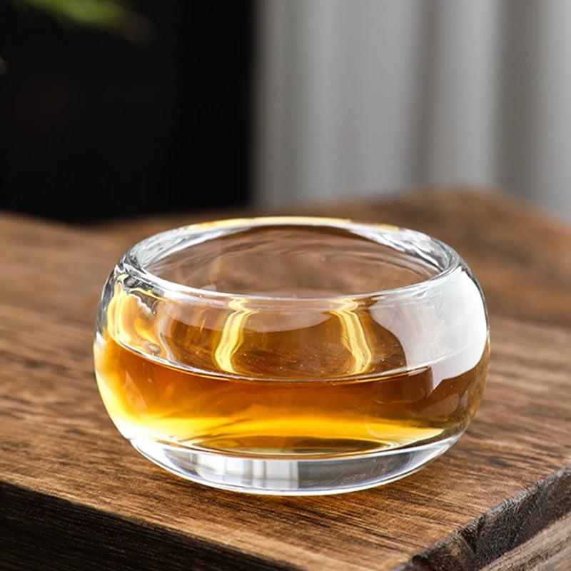 Tasse à thé en verre cristal épais remplie de thé, sur une planche en bois
