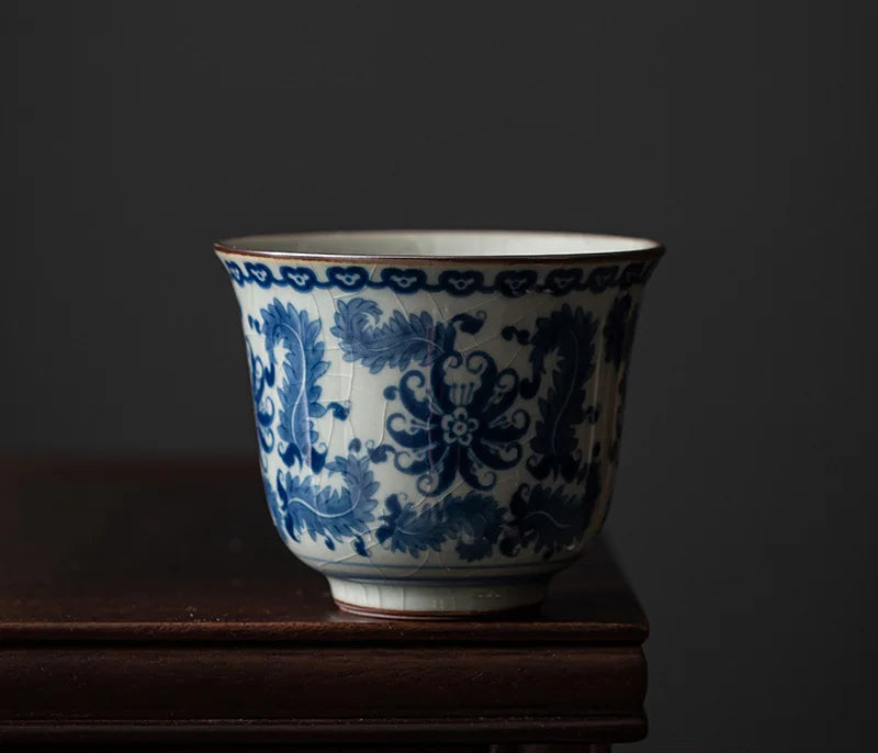 Tasse à thé au décor floral bleu en médaillon, posée sur un socle