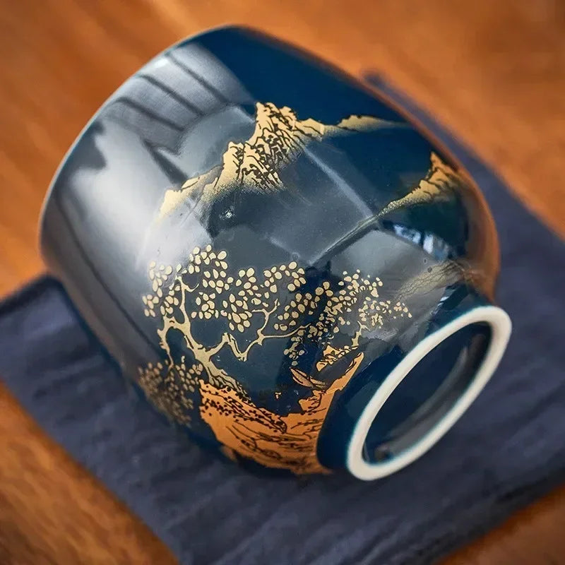 Tasse à thé renversée montrant son pied et son décor de paysage doré