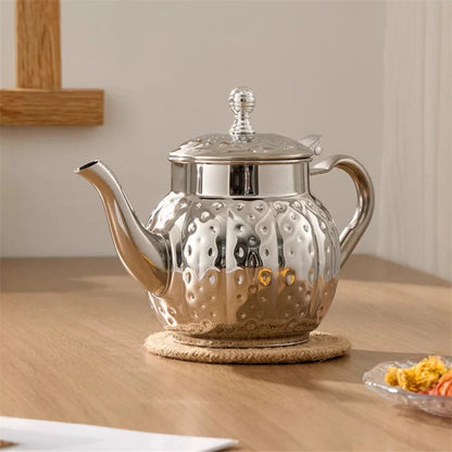 Théière inox martelé posée sur table élégante