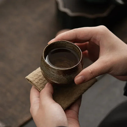 Tasse à thé en grès remplie d'infusion, tenue au creux de la main