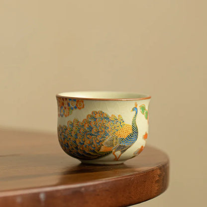 Tasse à thé en céramique craquelée à décor de paon, posée sur un socle en bois