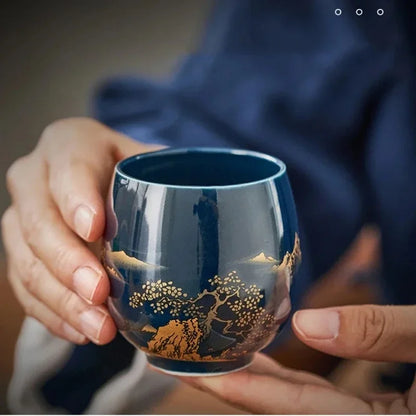 Gros plan sur le décor doré de pins et de montagnes de la tasse à thé