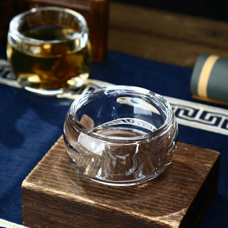 Deux tasses à thé en verre transparent posées sur un socle en bois