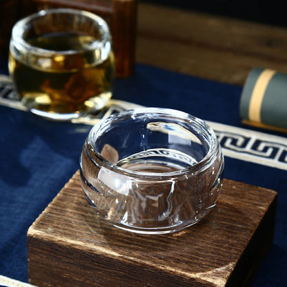 Deux tasses à thé en verre transparent posées sur un socle en bois