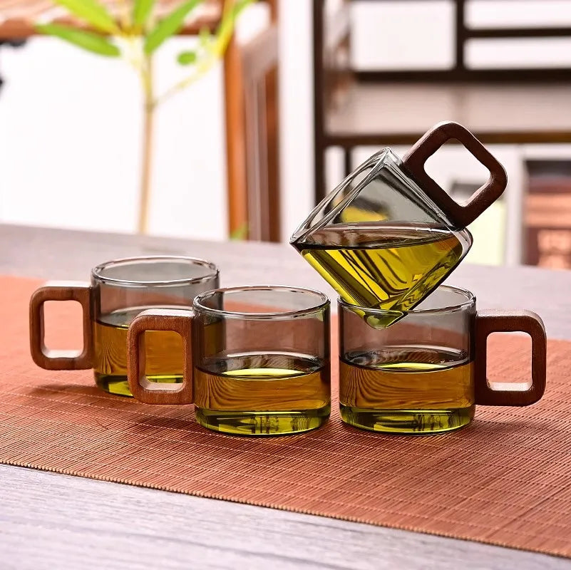 Quatre tasses à thé en verre à anse en bois alignées sur un chemin de table