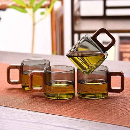 Quatre tasses à thé en verre à anse en bois alignées sur un chemin de table