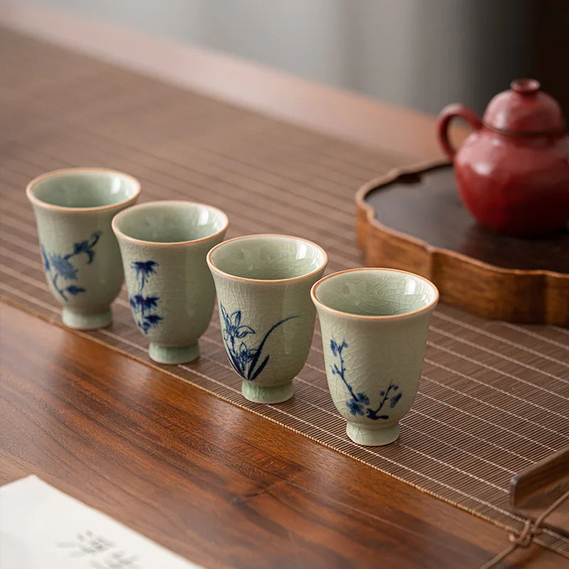 Lot de quatre tasses à thé céladon à décor floral bleu, alignées sur une table
