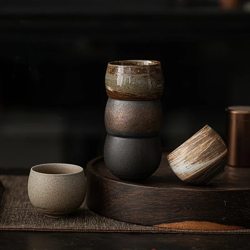Tasses à thé en grès aux teintes naturelles empilées sur un plateau en bois