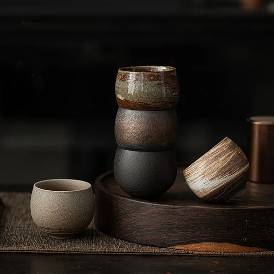 Tasses à thé en grès aux teintes naturelles empilées sur un plateau en bois