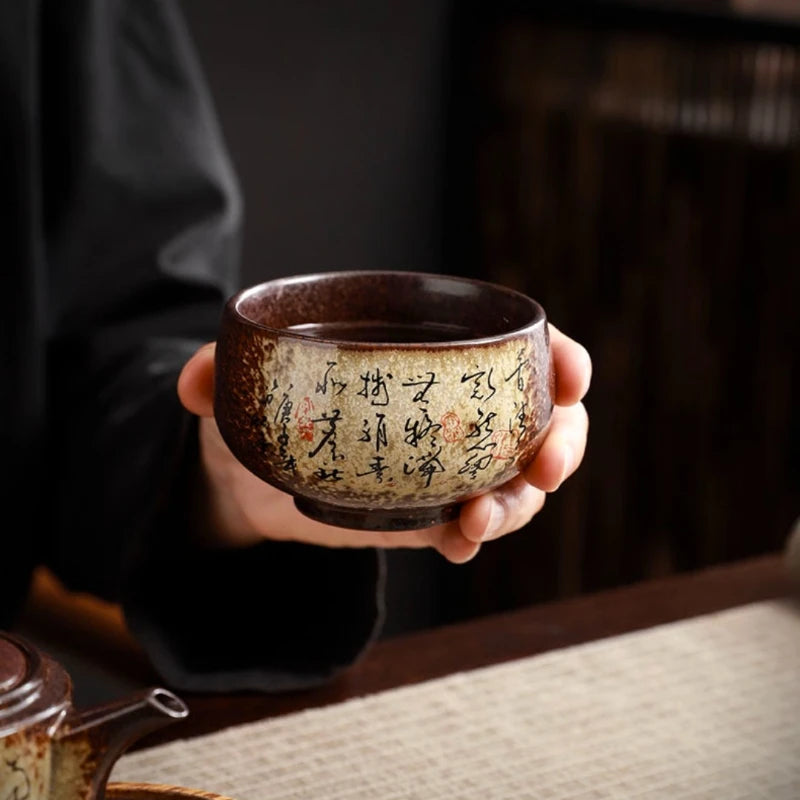 Tasse à thé en poterie calligraphiée tenue à deux mains