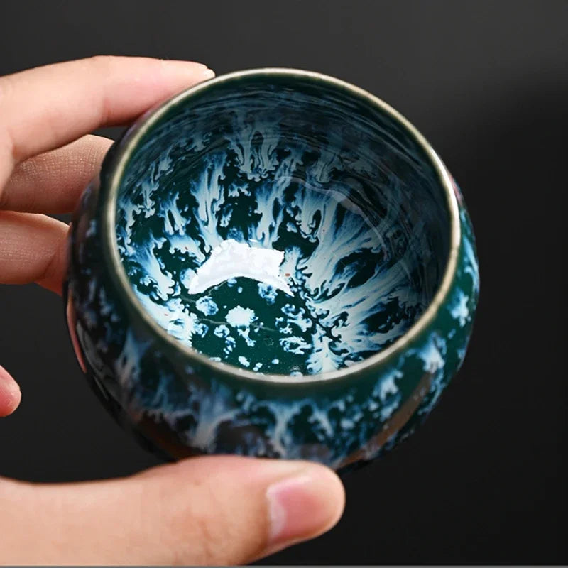 Intérieur d'une tasse à thé à glaçure bleu nuit mouchetée, tenue en main
