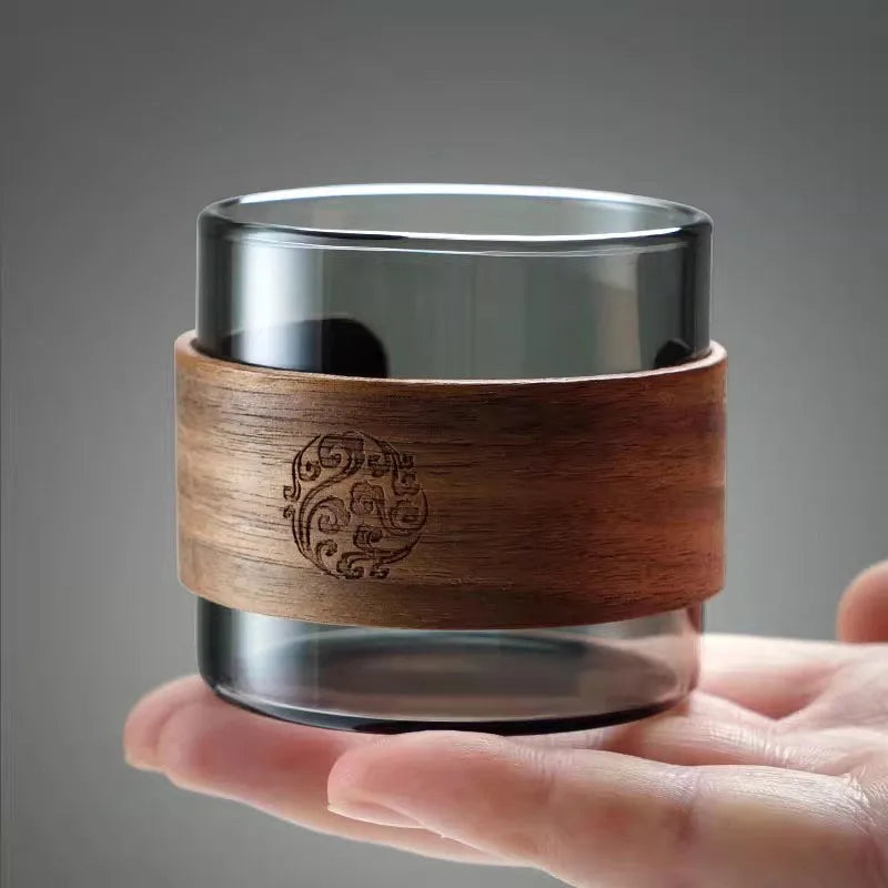Tasse à thé en verre et bois posée en équilibre sur une main