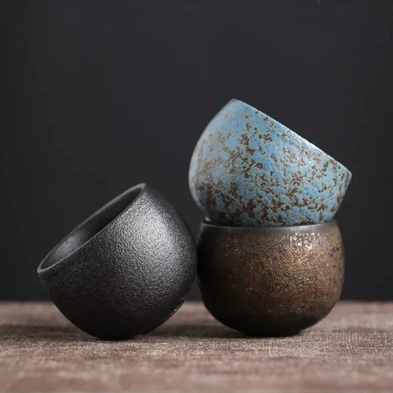 Les trois coloris de tasses à thé en grès empilés sur une toile de lin