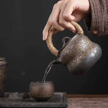 Théière en grès versant le thé dans la petite tasse assortie