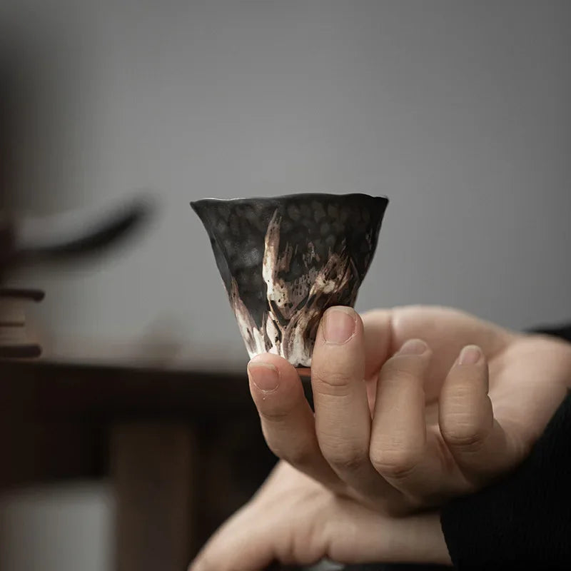 Tasse à thé en poterie brute de 50 ml tenue entre les doigts