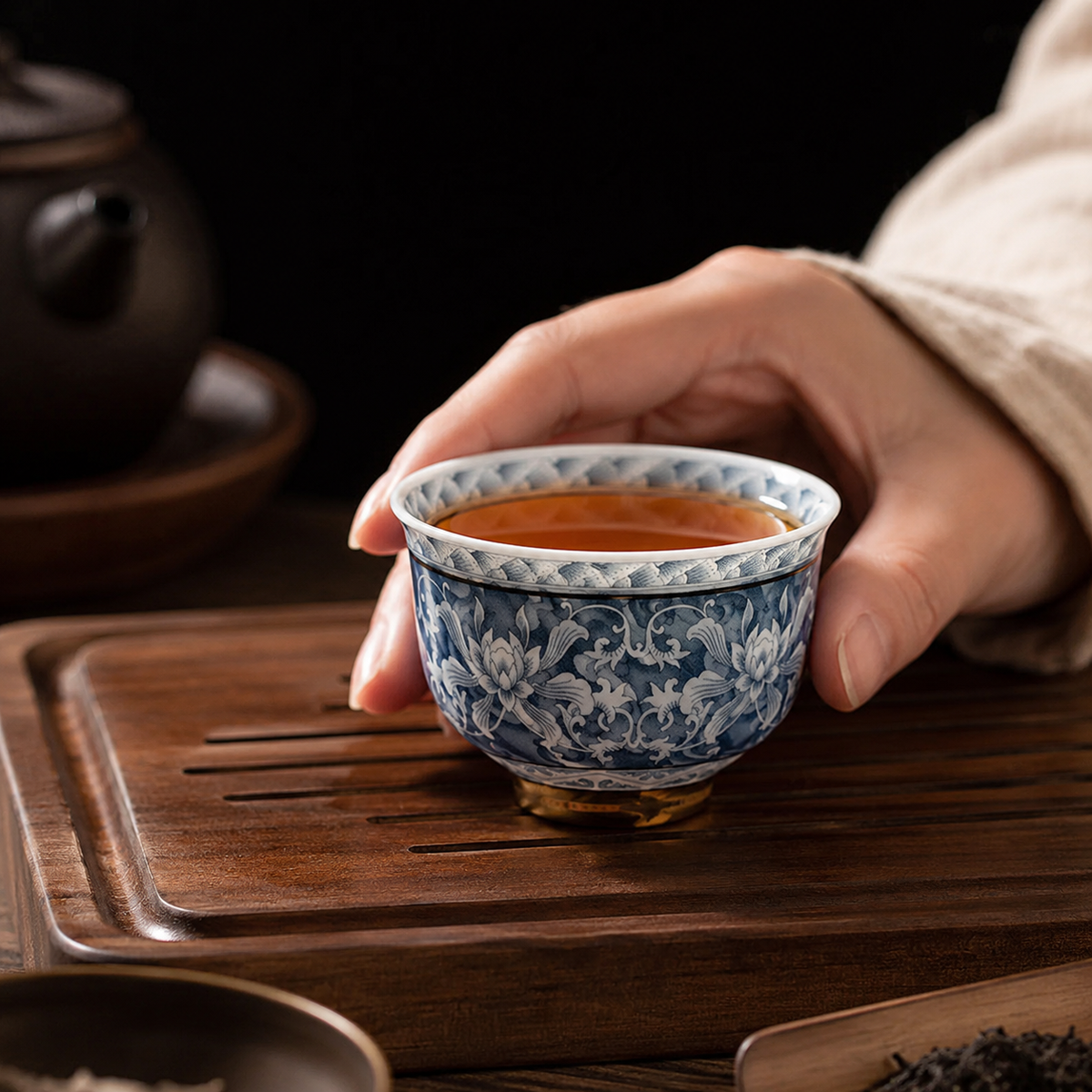 Bol à thé en porcelaine tenu en main au-dessus d'un plateau à thé