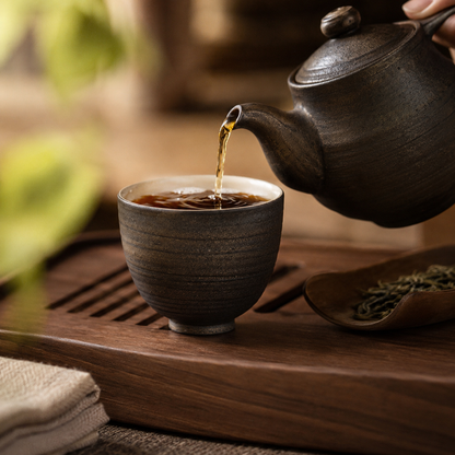 Théière en grès versant le thé dans la tasse à glaçure dorée