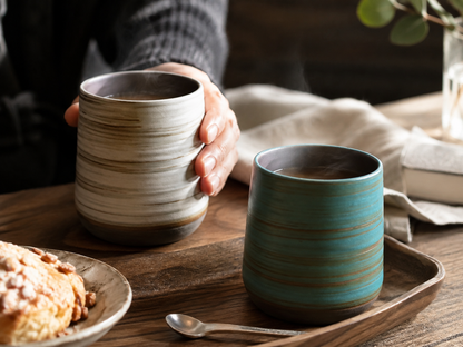Deux tasses à thé en grès sur un plateau, avec une viennoiserie