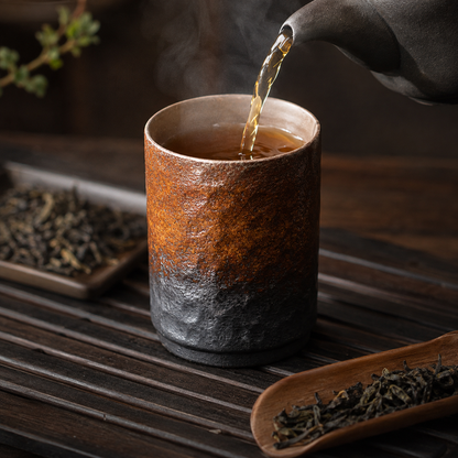Versement du thé dans la tasse en grès martelé posée sur un plateau