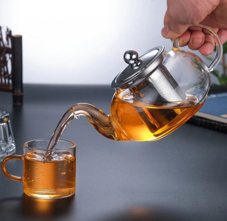 Thé versé depuis une théière en verre dans une tasse