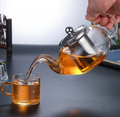 Thé versé depuis une théière en verre dans une tasse
